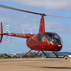 Robinson R44 Cadet hovers on an airfield