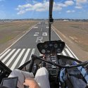 Cockpit view of helicopter flying over a runway